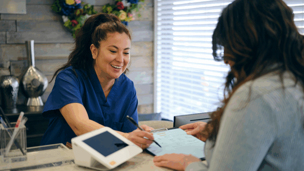 A patient checking in at the front desk of the dental office